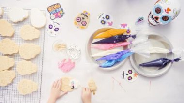 Anne ve kızı şeker kafatası kurabiye Dia de los Muertos tatil için Kraliyet buzlanma ile dekorasyon üstten görünüm.