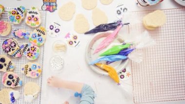 Küçük kız Dia de los Muertos tatil için Kraliyet buzlanma ile şeker kafatası çerezleri dekorasyon.