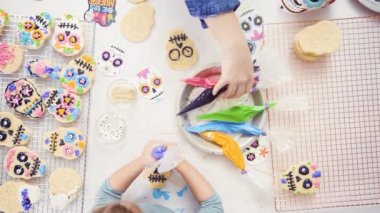 Anne ve kızı dekorasyon Dia de los Muertos tatil için Kraliyet buzlanma ile kafatası tanımlama şeker.