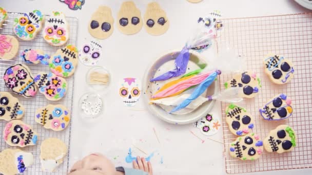 Kleines Mädchen Dekoriert Zuckerschädel Plätzchen Mit Königlichem Zuckerguss Für Dia — Stockvideo