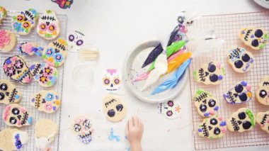 Küçük kız Dia de los Muertos tatil için Kraliyet buzlanma ile şeker kafatası çerezleri dekorasyon.