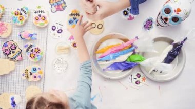 Anne ve kızı şeker kafatası kurabiye Dia de los Muertos tatil için Kraliyet buzlanma ile dekorasyon havai görünümü.