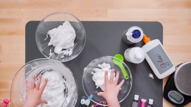 Adım adım. Anne ve kızı renkli kabarık slime yapmak.