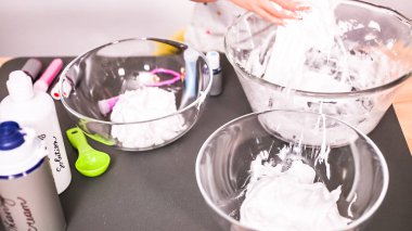 Adım adım. Anne ve kızı renkli kabarık slime yapmak.