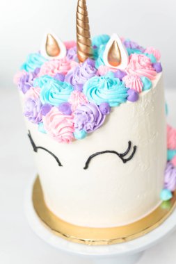 Pembe ve mor beyaz bir arka plan üzerinde buzlanma buttercream ile gurme tek boynuzlu at pasta.
