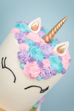 Pembe ve mor mavi arka plan üzerinde buzlanma buttercream ile gurme tek boynuzlu at pasta.
