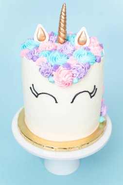 Pembe ve mor mavi arka plan üzerinde buzlanma buttercream ile gurme tek boynuzlu at pasta.