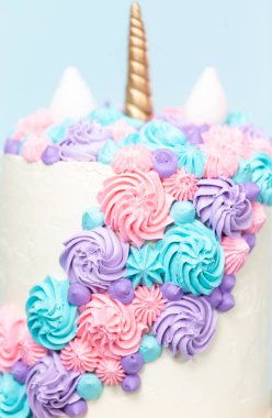 Pembe ve mor mavi arka plan üzerinde buzlanma buttercream ile gurme tek boynuzlu at pasta.