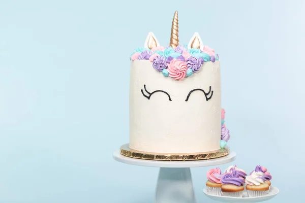 Gourmet unicorn cake with pink and purple buttercream frosting on blue background.