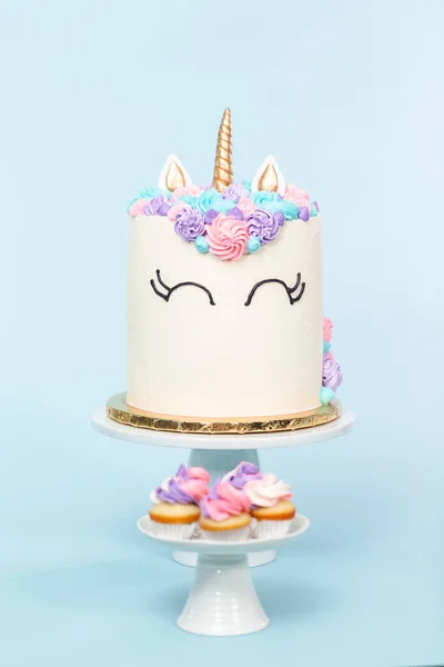 美食独角兽蛋糕与粉红色和紫色的奶油霜在蓝色背景 — 图库照片