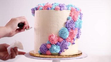 Tek boynuzlu at gözleri siyah bir buttercream beyaz bir kek üzerine krema ile boru.