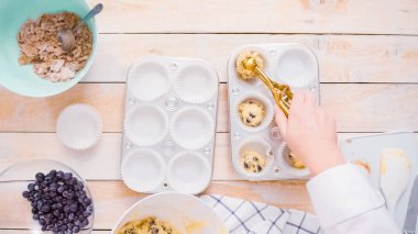 Yaban mersinli kek hamuru metal muffin tava içine scooping.