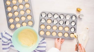 Düz yatıyordu. Cupcake gömlekleri içine vanilyalı kek hamuru scooping.