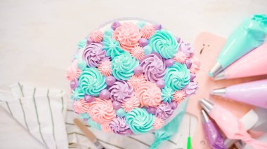 Düz yatıyordu. Bir tek boynuzlu at yapmak için beyaz bir kek üzerine pastel renk buttercream rozet Boru hattların başka şekilli pasta.