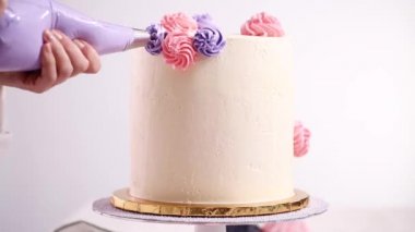 Zaman atlamalı. Düz yatıyordu. Bir tek boynuzlu at yapmak için beyaz bir kek üzerine pastel renk buttercream rozet Boru hattların başka şekilli pasta.