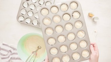 Düz yatıyordu. Cupcake gömlekleri içine vanilyalı kek hamuru scooping.