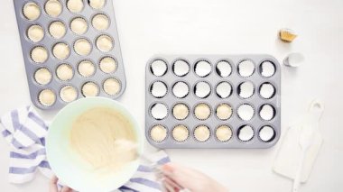 Düz yatıyordu. Cupcake gömlekleri içine vanilyalı kek hamuru scooping.