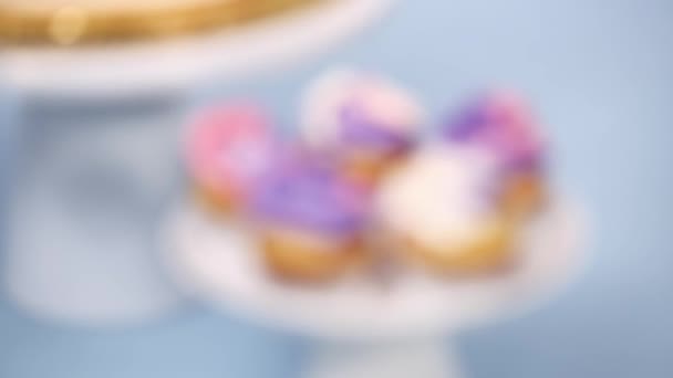 在小香草纸杯蛋糕上运送粉红色和紫色的奶油糖霜 — 图库视频影像