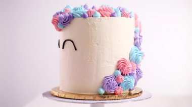 Tek boynuzlu at gözleri siyah bir buttercream beyaz bir kek üzerine krema ile boru.