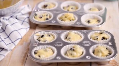 Yaban mersinli kek hamuru metal muffin tava içine scooping.