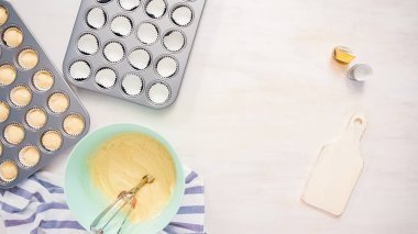 Düz yatıyordu. Cupcake gömlekleri içine vanilyalı kek hamuru scooping.