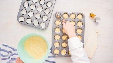 Düz yatıyordu. Cupcake gömlekleri içine vanilyalı kek hamuru scooping.