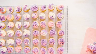 Düz yatıyordu. Pembe ve mor buttercream frosting küçük vanilyalı kek üzerinde boru.