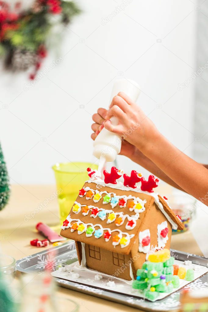 Kids decorating small gingerbread houses at the Christmas craft party.