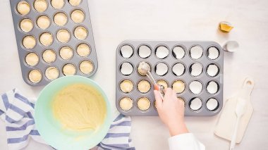 Düz yatıyordu. Cupcake gömlekleri içine vanilyalı kek hamuru scooping.