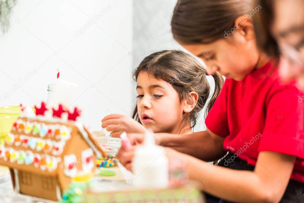 Kids decorating small gingerbread houses at the Christmas craft party.