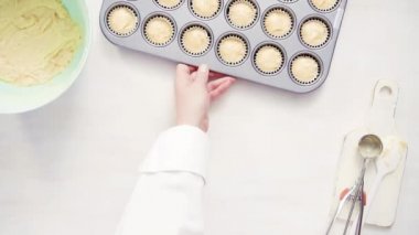 Düz yatıyordu. Cupcake gömlekleri içine vanilyalı kek hamuru scooping.