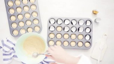 Düz yatıyordu. Cupcake gömlekleri içine vanilyalı kek hamuru scooping.