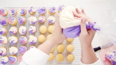 Düz yatıyordu. Pembe ve mor buttercream frosting küçük vanilyalı kek üzerinde boru.