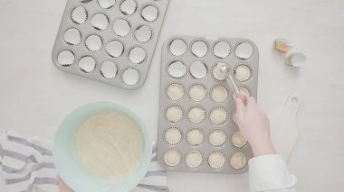 Düz yatıyordu. Cupcake gömlekleri içine vanilyalı kek hamuru scooping.