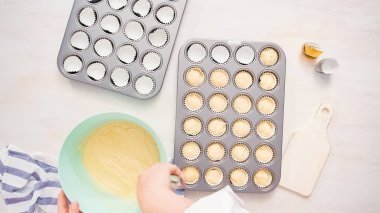 Düz yatıyordu. Cupcake gömlekleri içine vanilyalı kek hamuru scooping.