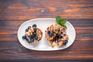 Düz yatıyordu. Ev yapımı blueberry muffins beyaz bir tabağa dilimlenmiş.