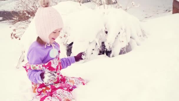 慢动作 戴粉色帽子在雪地里玩耍的小女孩 — 图库视频影像
