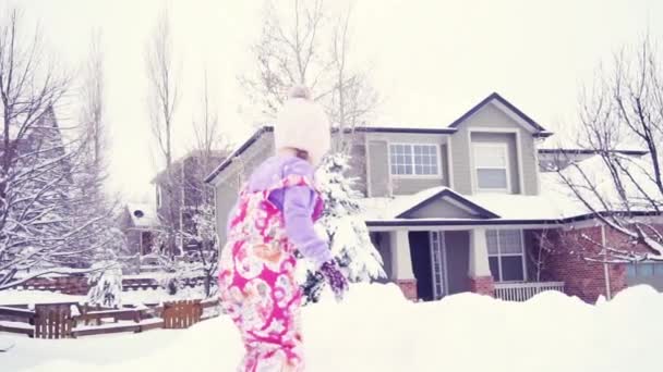 スローモーション 雪の中で遊ぶピンクの帽子の女の子 — ストック動画
