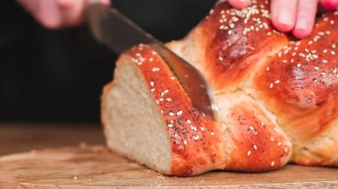 Adım adım. Taze pişmiş shallah ekmeğini susam ve haşhaş tohumuyla dilimliyorum..