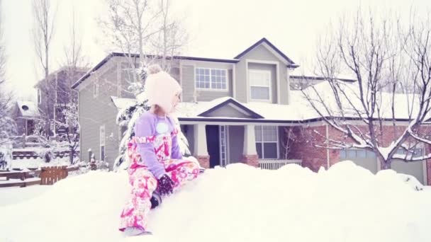 スローモーション 雪の中で遊ぶピンクの帽子の女の子 — ストック動画