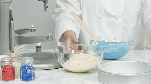 Step by step. Mixing food coloring into a cake batter to bake a three-layer vanilla cake.