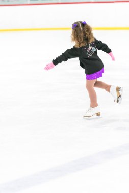 Küçük kız buz pateni pistinde artistik patinaj yapıyor..