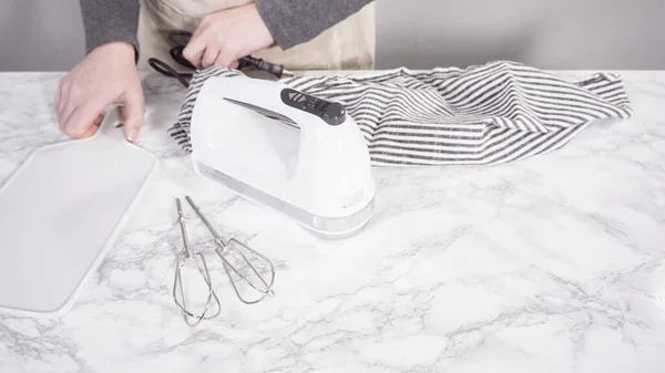 Step by step. White hand mixer on a marble kitchen surface.