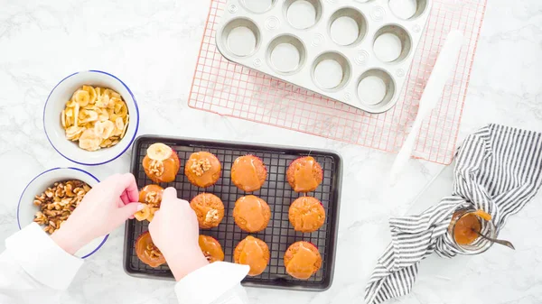 Flat lay. Step by step. Garnishing banana bread muffins with homemade caramel, banana chips,  and walnuts.