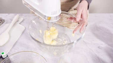 Adım adım. Vanilyalı Mardi Gras kekleri pişirmek için karışımı elektrikli mikserle karıştırıyorum..