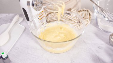 Adım adım. Vanilyalı Mardi Gras kekleri pişirmek için karışımı elektrikli mikserle karıştırıyorum..