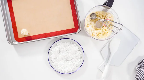 Flat lay. Scooping cookie dough into the baking sheet to bake coconut cookies.