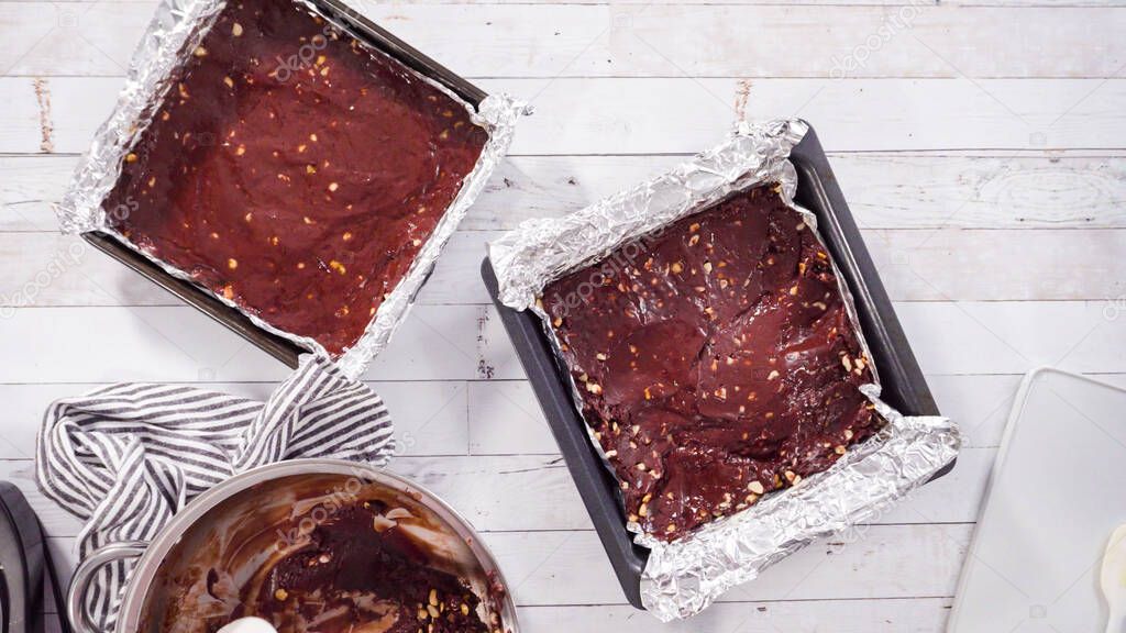 Flat lay. Step by step. Scooping melted chocolate into baking pans lined with cooking foil to make macadamia nut fudge.
