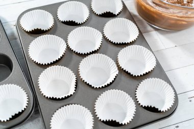 Çikolatalı ahududu kekleri pişirmek için folyolu kek bardaklarıyla kaplı kek tepsisi..