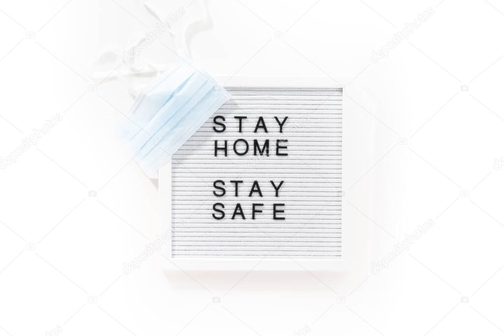 STAY HOME and STAY SAFE sign on message board with a blue medical mask.